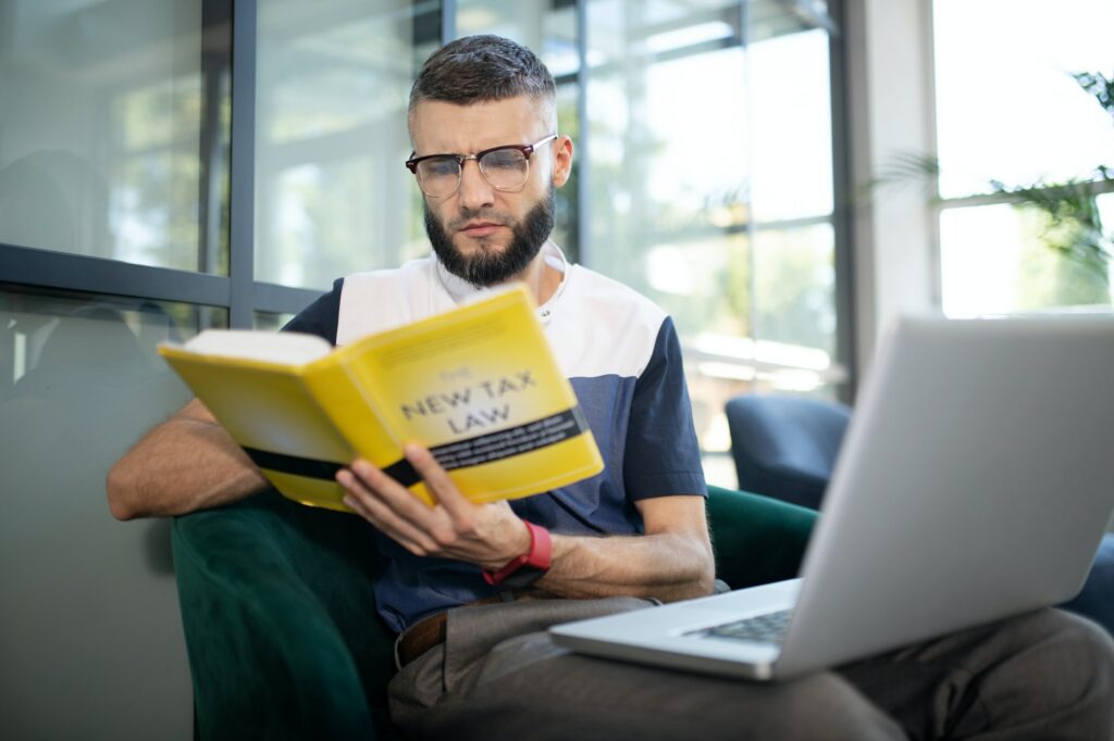 Bearded businessman wearing glasses reading tax book