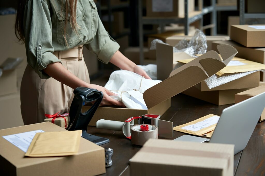 Female online store business owner packing ecommerce shipping box.