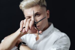 Hairdresser stylist holding scissors on black background, focus on scissors